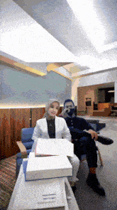 a woman in a hijab sits next to a man in a chair