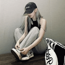 a woman wearing a black hat is sitting on the floor tying her shoes