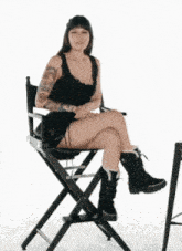 a woman sits in a directors chair with her legs crossed