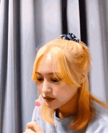 a woman with blonde hair is holding a pink lollipop in her hand