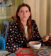 a woman is sitting at a table eating cereal from a box that says ' strawberry '