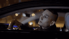 a man with a tattoo on his face is driving a car at night .