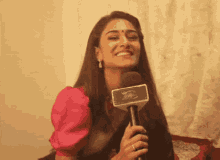 a woman is smiling while holding a microphone which says ' aaj ' on it