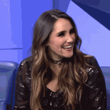 a woman wearing a choker and a microphone smiling