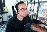 a man wearing headphones and glasses is sitting at a desk with a microphone