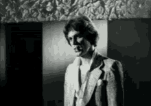 a man in a suit stands in front of a wall