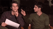 two young men are sitting next to each other in a chair .