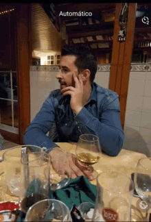 a man sits at a table with a glass of wine and a bottle of 1822