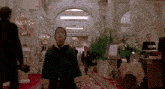 a boy in a green coat is walking through a hallway