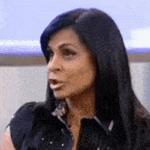 a woman with long black hair is making a funny face while sitting on a couch .