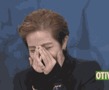 a woman covering her face with her hands in front of a sign that says otti