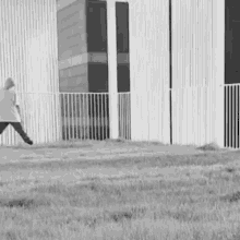 a black and white photo of a man walking in front of a building .