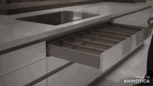 a person is opening a drawer in a kitchen with the words made in animatica on the bottom