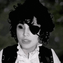 a black and white photo of a woman wearing a pirate costume and sunglasses .