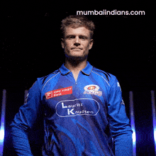 a man wearing a blue shirt with the website mumbaiindians.com on the bottom right