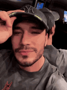 a man with a beard wearing a hat with the letter x on it