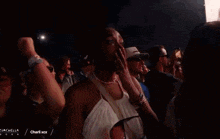 a woman is crying in a crowd of people at a concert while another woman holds her hand to her face .