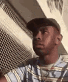 a man wearing a hat and a striped shirt is looking at the camera .