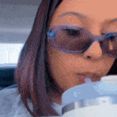 a woman wearing sunglasses is drinking from a straw