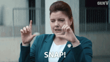 a woman in a blue jacket making a snap sign