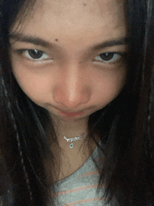a close up of a woman 's face with a necklace that says ' squids ' on it