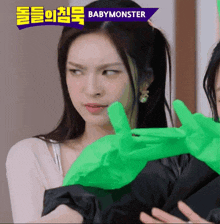 a woman wearing green gloves with the word babymonster on top