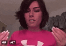 a woman in a pink under armour shirt is making a face .