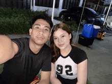 a man and a woman are posing for a picture and the woman is wearing a number 92 shirt