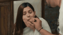 a man is feeding a woman a piece of food with his hand .