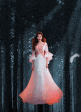 a woman in a long white dress is standing in a forest