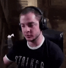 a man wearing headphones and a black shirt is sitting in a chair in a dark room .