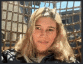 a woman with blonde hair is sitting in a chair with a wicker fence in the background