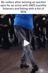 a man in a blue shirt is dancing in front of a group of people