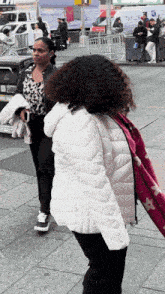 a woman in a white jacket stands next to a woman in a black jacket