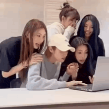 a group of women are looking at a laptop computer .