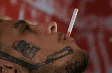 a man with a tattoo on his face is smoking a cigarette with a needle in his mouth .