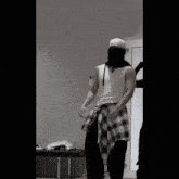 a man wearing a bandana and a plaid shirt stands in a room