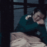 a man is laying in bed with his head on his hand .