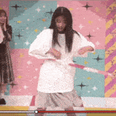 a woman is playing with a hula hoop in front of a colorful background
