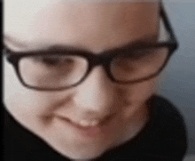 a close up of a person wearing glasses and a black shirt .