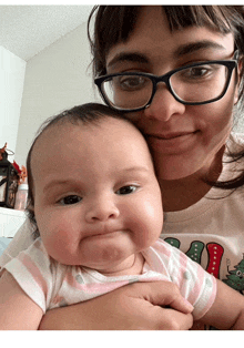 a woman with glasses is holding a baby in her arms