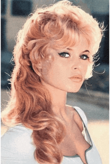 a woman with long blonde hair and blue eyes is wearing a white shirt