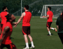 a group of men in red shirts and shorts are standing on a field