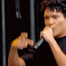 a man is singing into a microphone and making a peace sign with his hands .