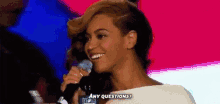 a woman is holding a microphone in her hand and smiling while asking any questions .