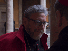 a man with glasses and a beard is wearing a red coat