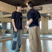 two men are standing next to each other in a dance studio talking to each other .