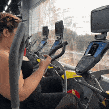 a woman is sitting on an elliptical machine in a gym