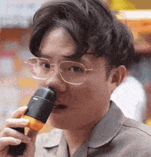a man wearing glasses is drinking from a bottle
