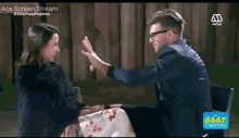 a man and a woman are giving each other a high five while sitting at a table